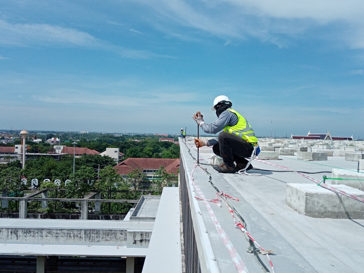 วิศวกรสำรวจหน้างานและวัดระยะโครงข่ายบนดาดฟ้าตึกเพื่อประเมินราคาและออกแบบติดตั้ง ระบบสายล่อฟ้า