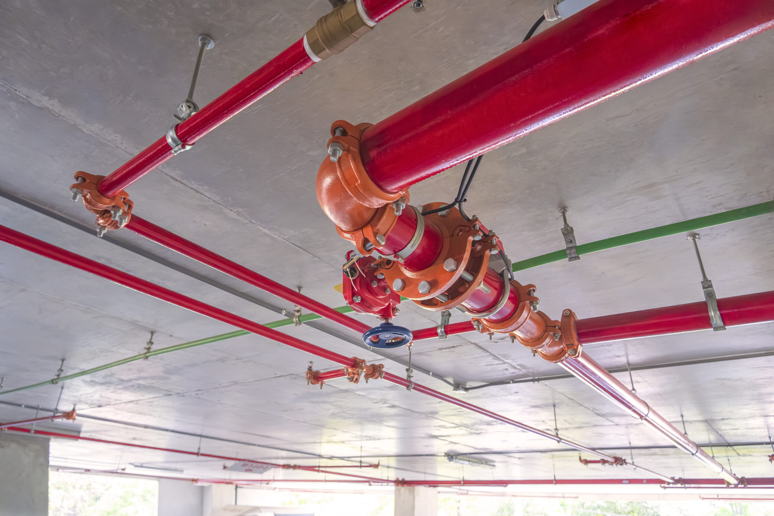 red fire protective water pipeline system concrete ceiling inside parking garage scaled